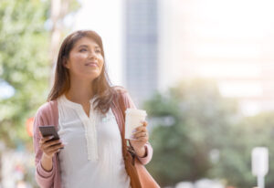 コーヒーを持ち散歩する女性