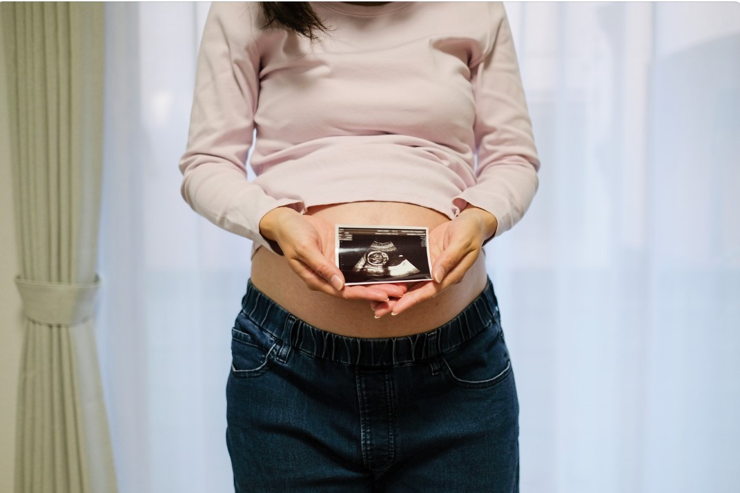 エコー写真をお腹の前で持つ妊婦