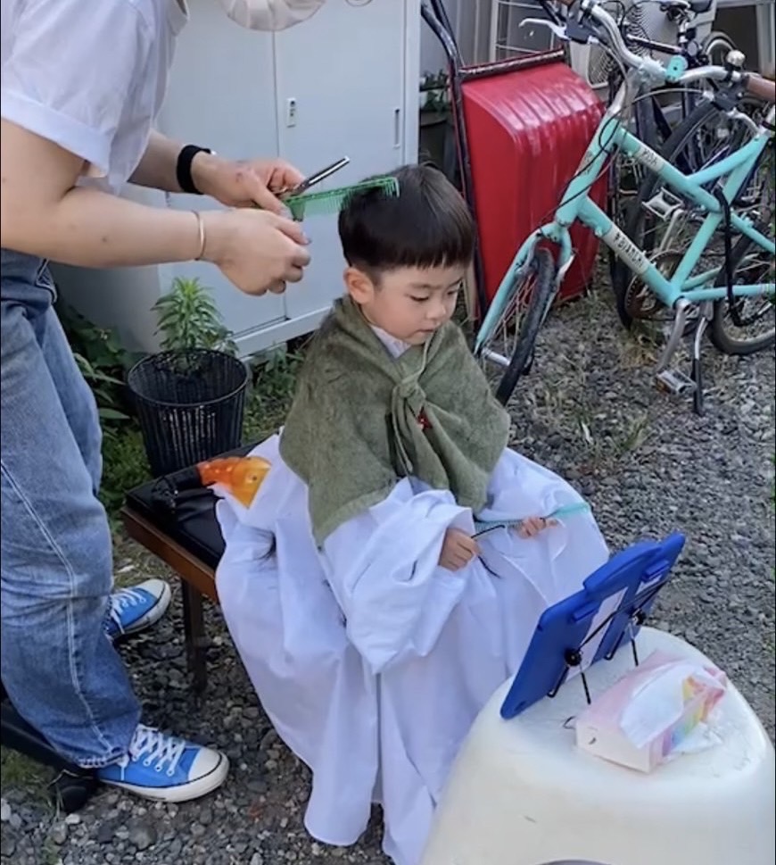 外で髪を切る男の子