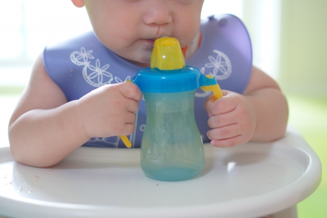 赤ちゃんがマグボトルを持っている
