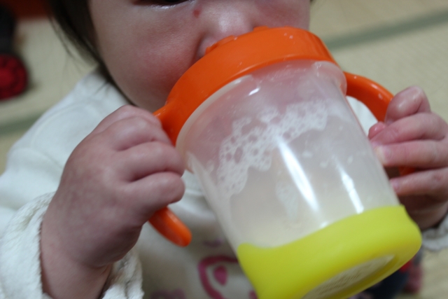 赤ちゃんがマグでミルクを飲んでいる