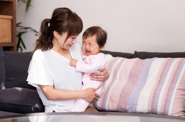 泣いている赤ちゃんを抱っこする母親