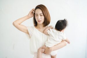 子どもを抱いて悩む女性